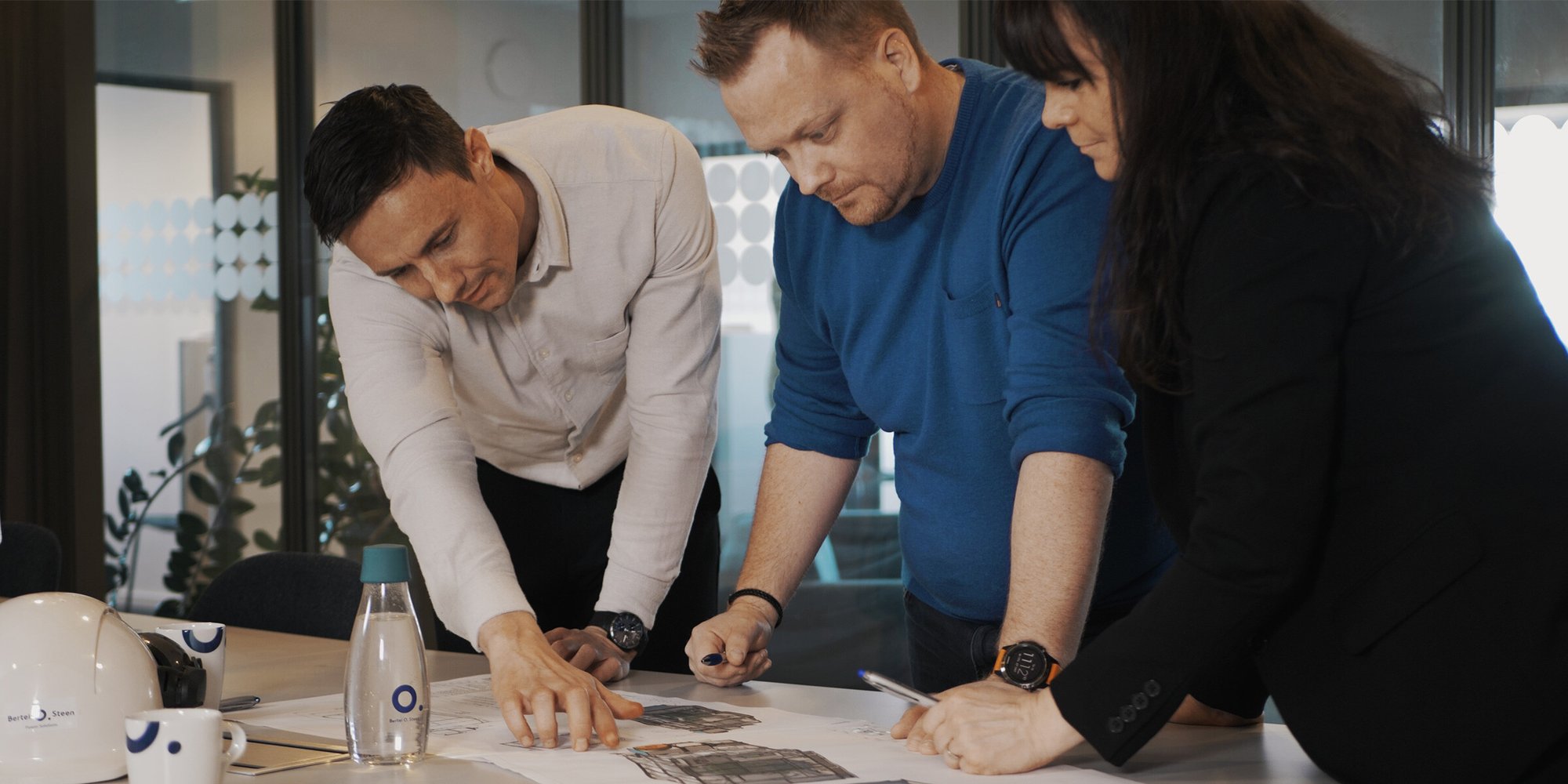 Et team på tre personer, der samarbejder om dokumenter på kontoret. Et team på tre personer, der samarbejder om dokumenter på kontoret.